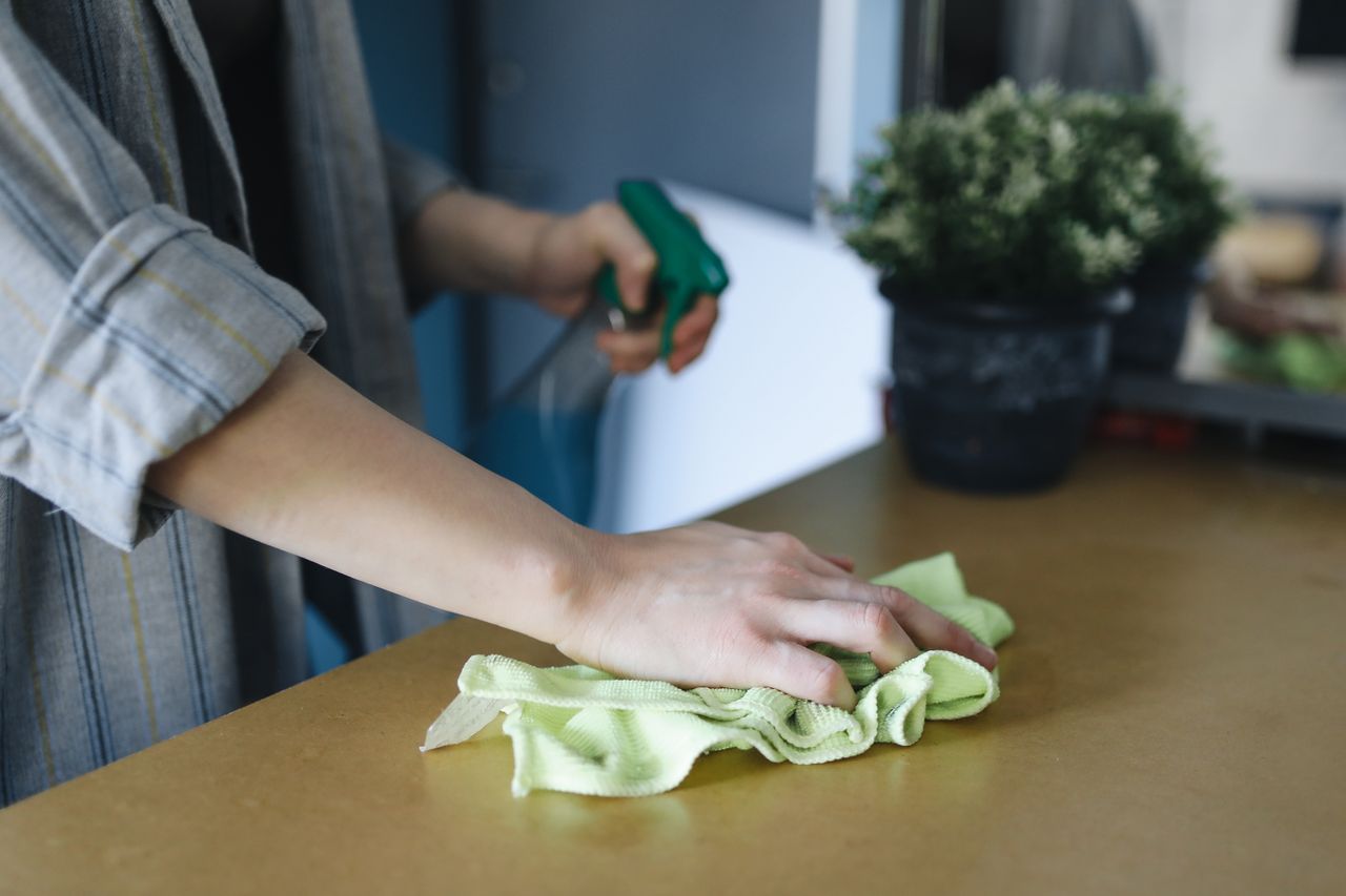 Crafting Captivating Headlines: Your awesome post title goes here Close-up of a woman wiping a table with a spray bottle and cloth indoors, symbolizing effective housekeeping.